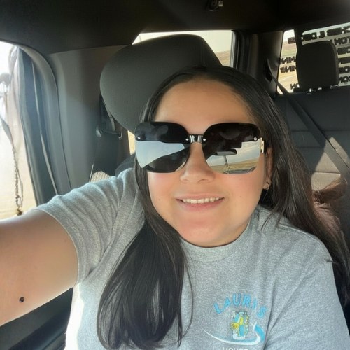 Laura Ruiz wearing a Lauri’s House Cleaning shirt in a vehicle.
